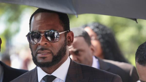 R. Kelly beard glasses holding umbrella